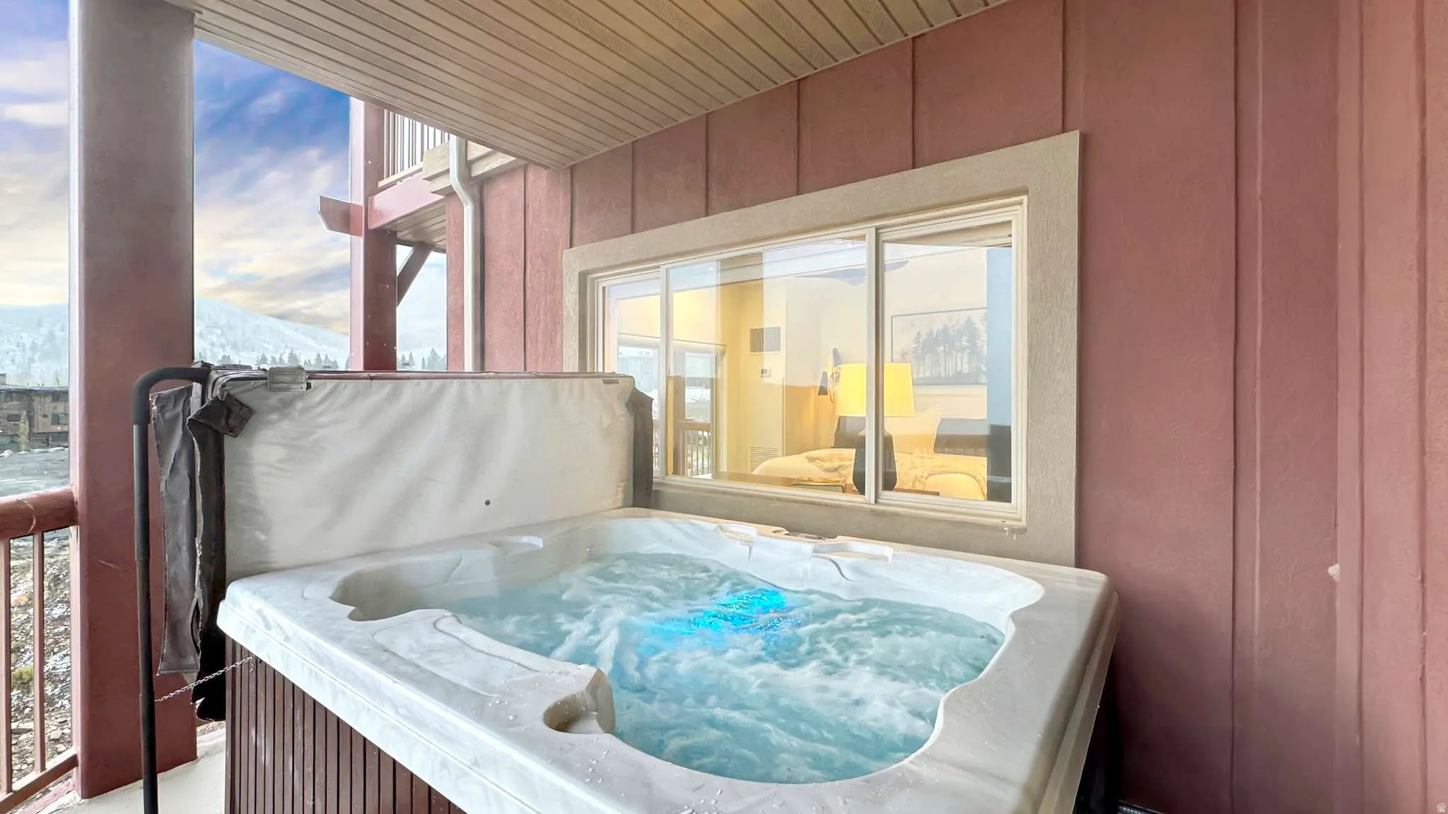 Private outdoor hot tub with integrated lighting, wood-paneled base, and mountain scenery