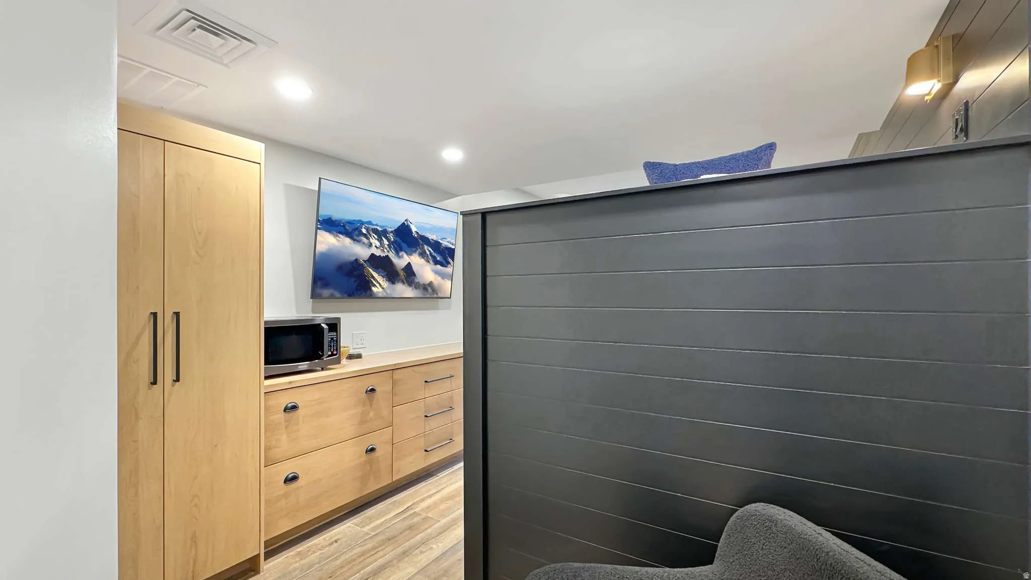 Built-in blonde wood cabinetry with matte black hardware, integrated storage, and recessed lighting