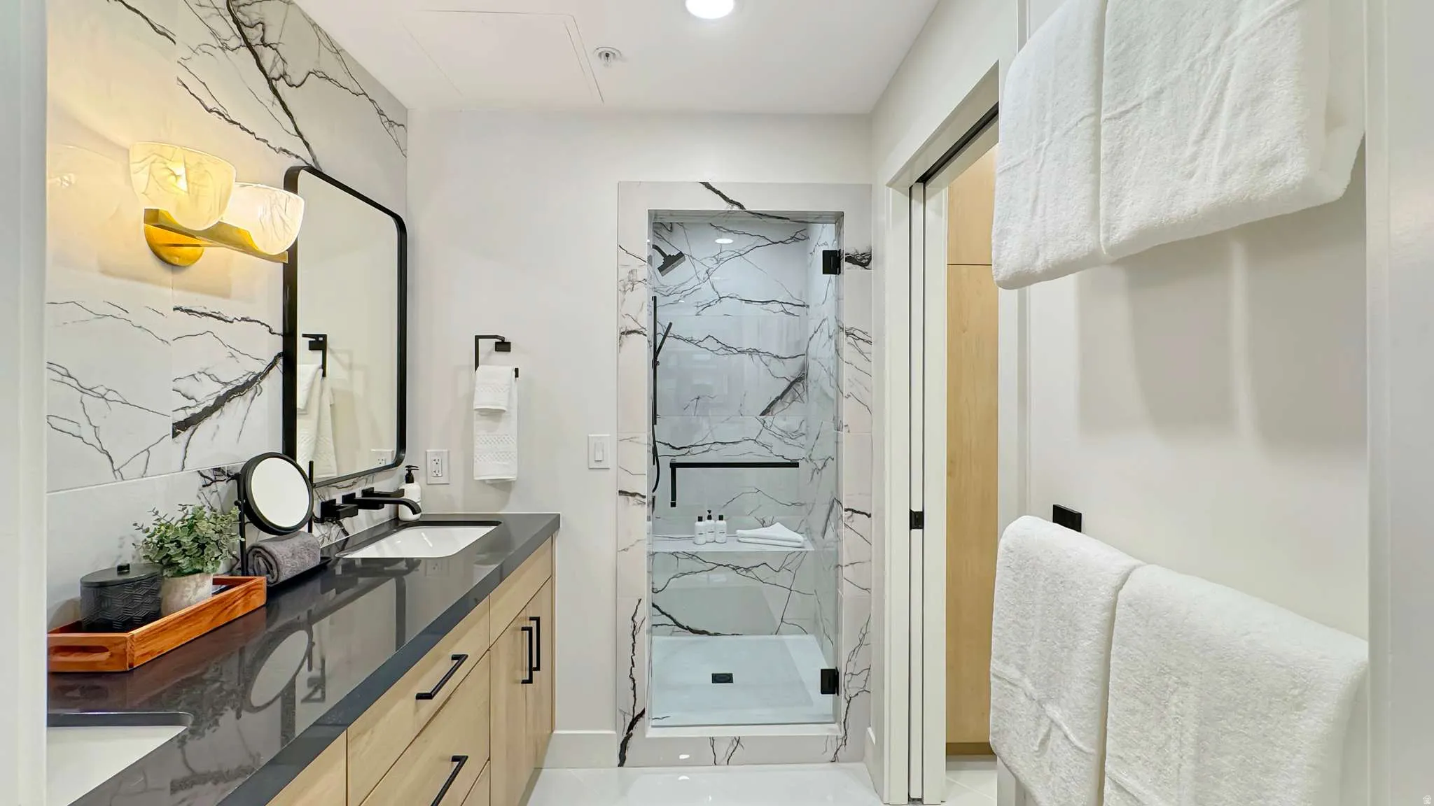 Bathroom featuring a dual vanity with wood-finish cabinetry, dark countertop, and integrated sinks