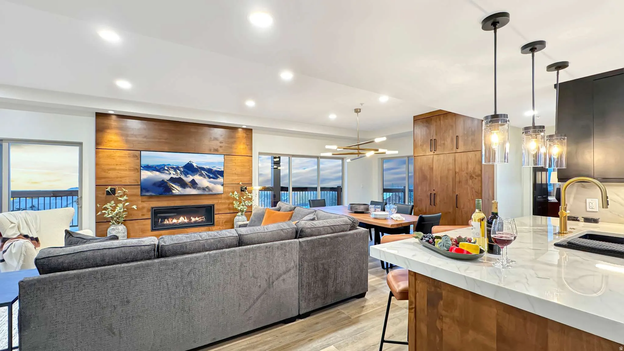 Open-concept living space featuring a wood-panelled accent wall with an inset fireplace and television
