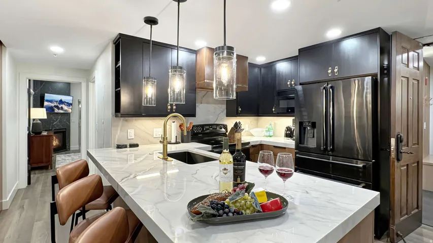 Contemporary kitchen featuring a large island with a waterfall countertop, integrated sink with a gold-tone faucet, and pendant lighting