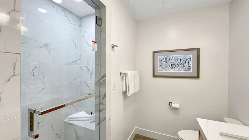 Shower enclosure with clear glass door, chrome hardware, and white marble-look tile