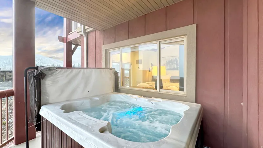 Private outdoor hot tub with integrated lighting, wood-paneled base, and mountain scenery