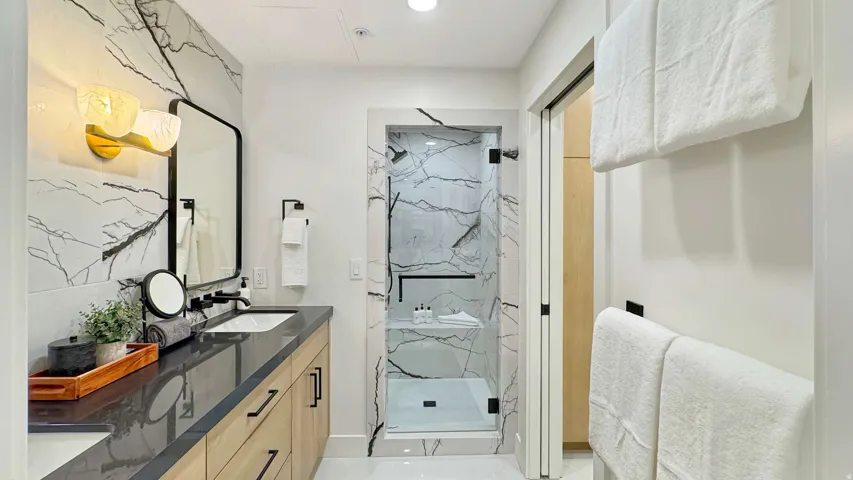 Bathroom featuring a dual vanity with wood-finish cabinetry, dark countertop, and integrated sinks