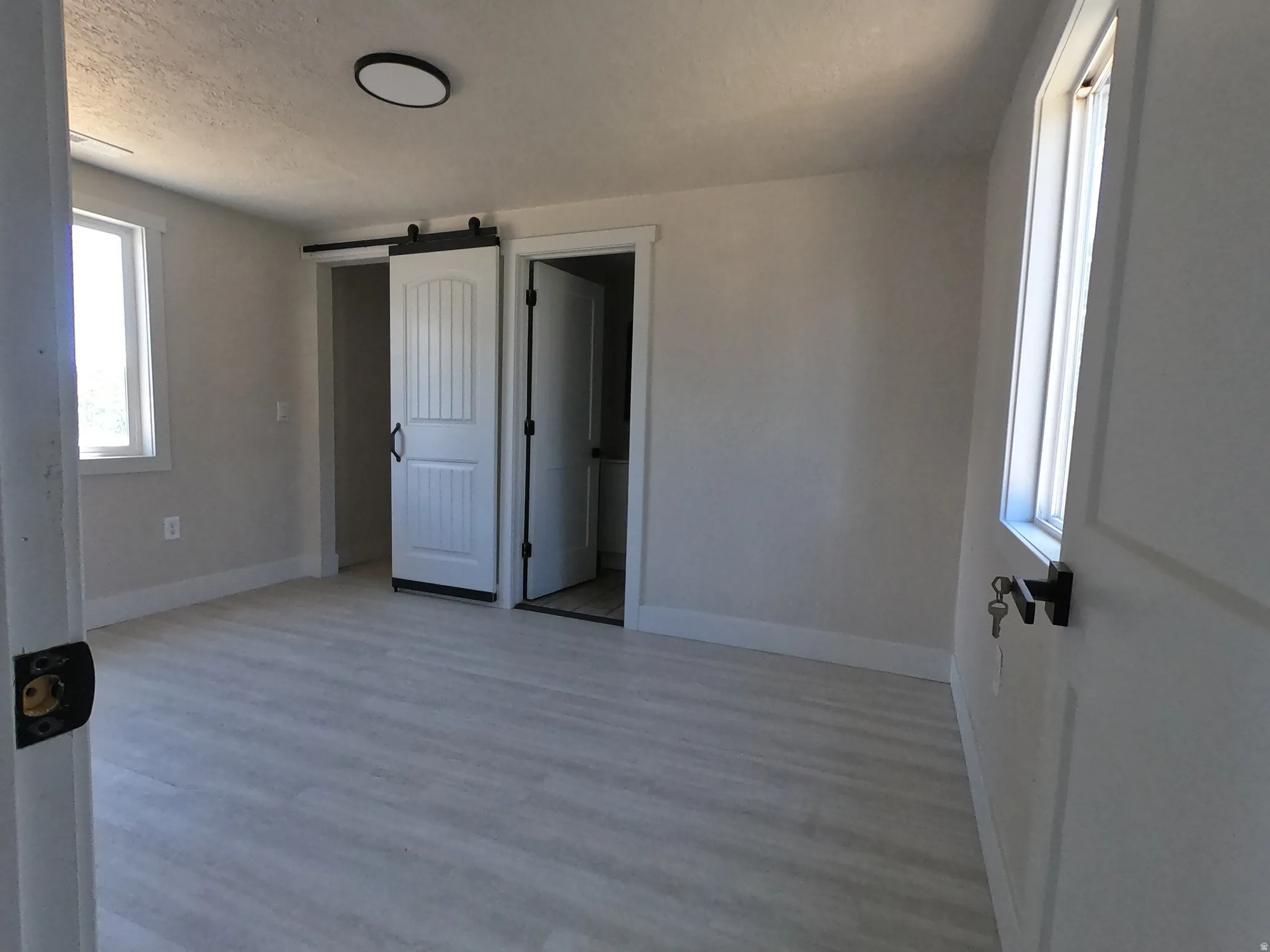 Spacious room featuring light wood-finish flooring, white baseboards, and neutral wall tones
