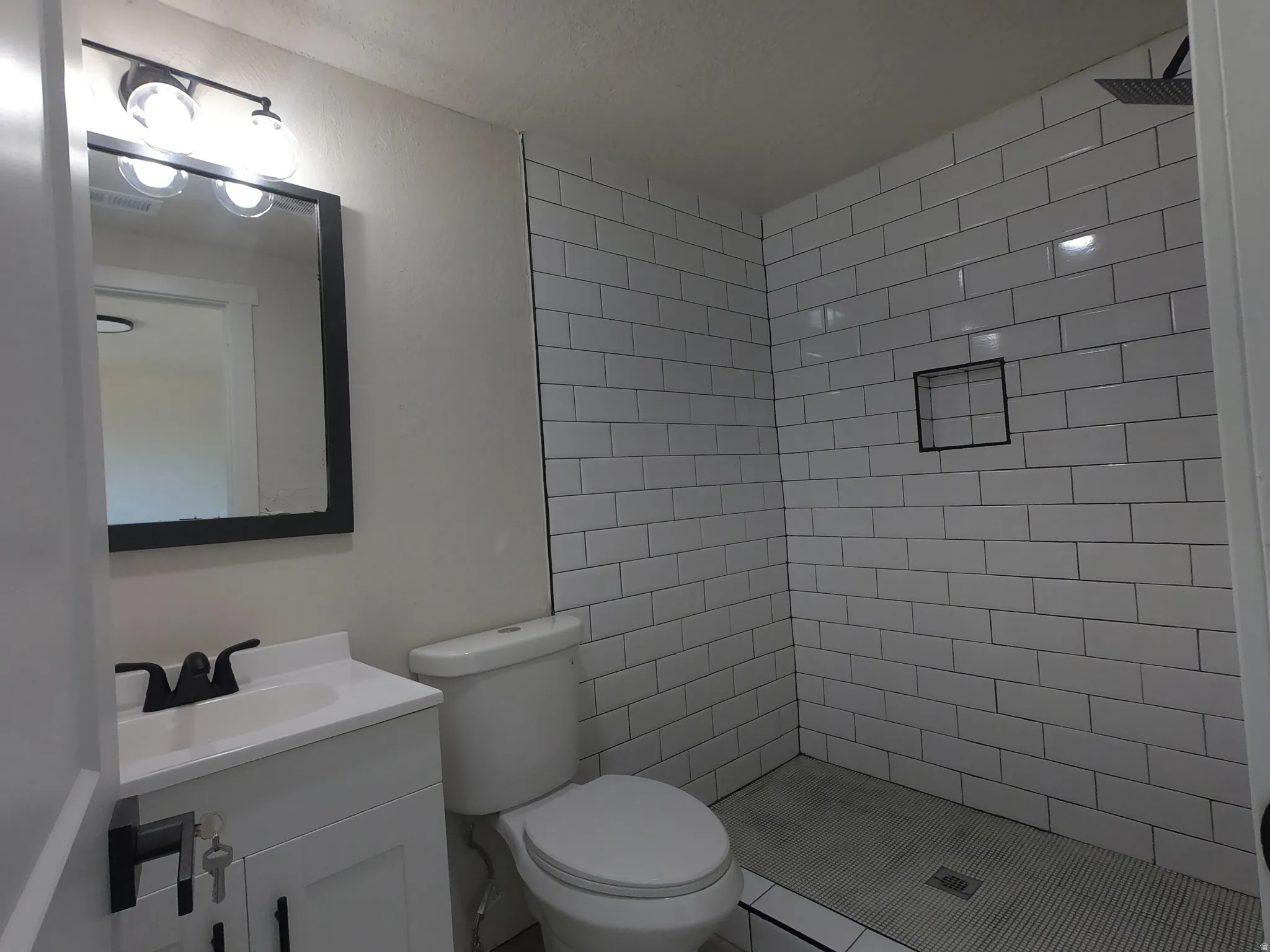 Contemporary bathroom featuring a subway-tiled shower with a rainfall showerhead and built-in niche