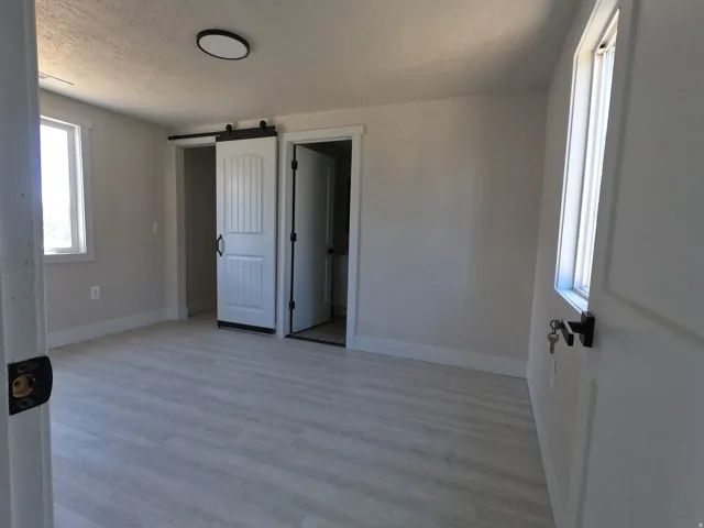 Spacious room featuring light wood-finish flooring, white baseboards, and neutral wall tones
