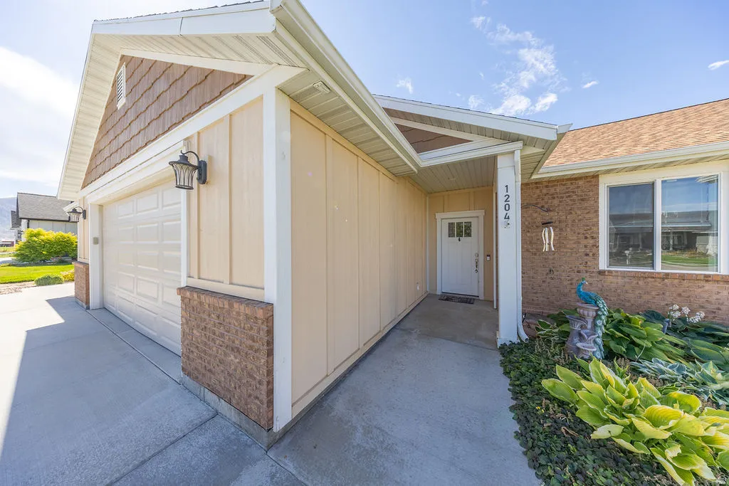 Exterior featuring a two-car garage with a panel door, brick accents, and shake siding