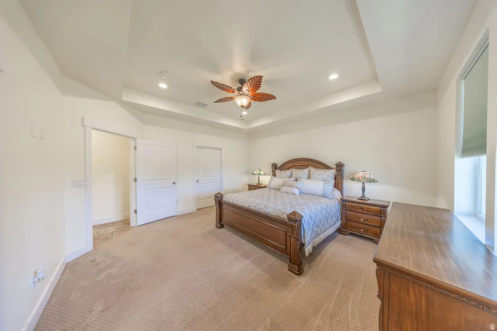Spacious room featuring a tray ceiling with recessed lighting and a ceiling fan