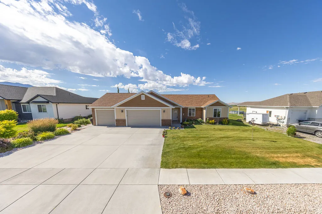 Ranch-style residence featuring a two-car garage, concrete driveway, and a front lawn