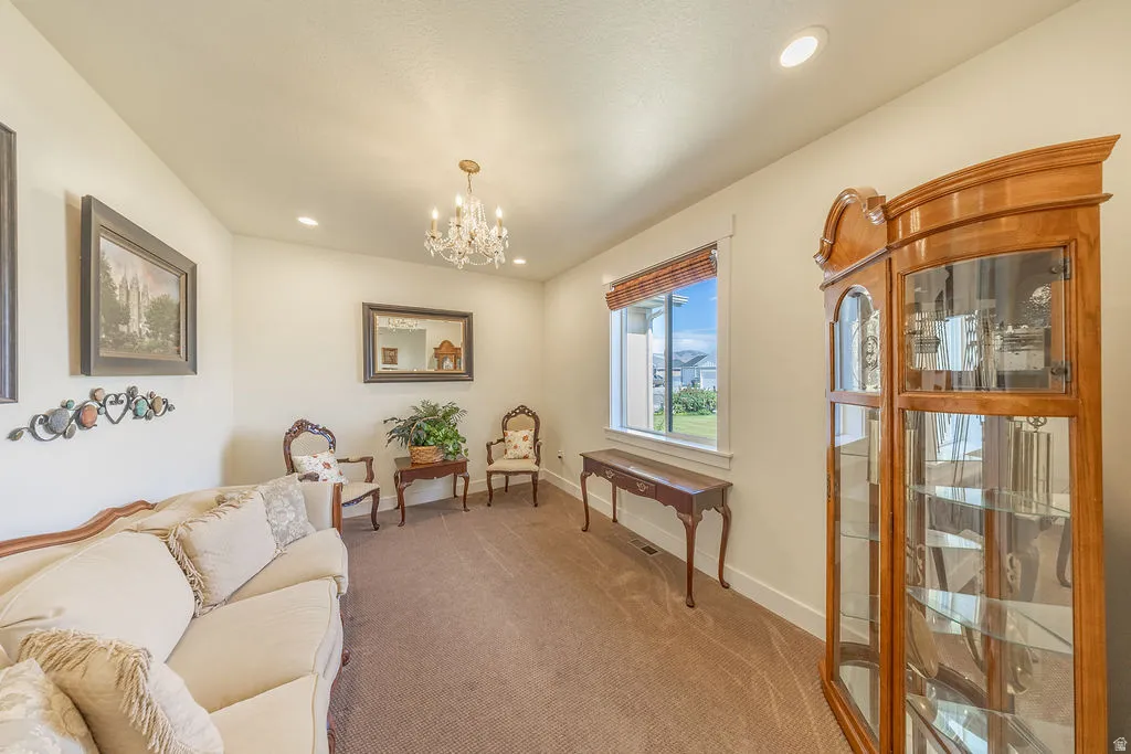 Spacious room featuring neutral wall tones, recessed lighting, a large window with privacy window shades, and a durable carpeted floor.  Chandelier is excluded.