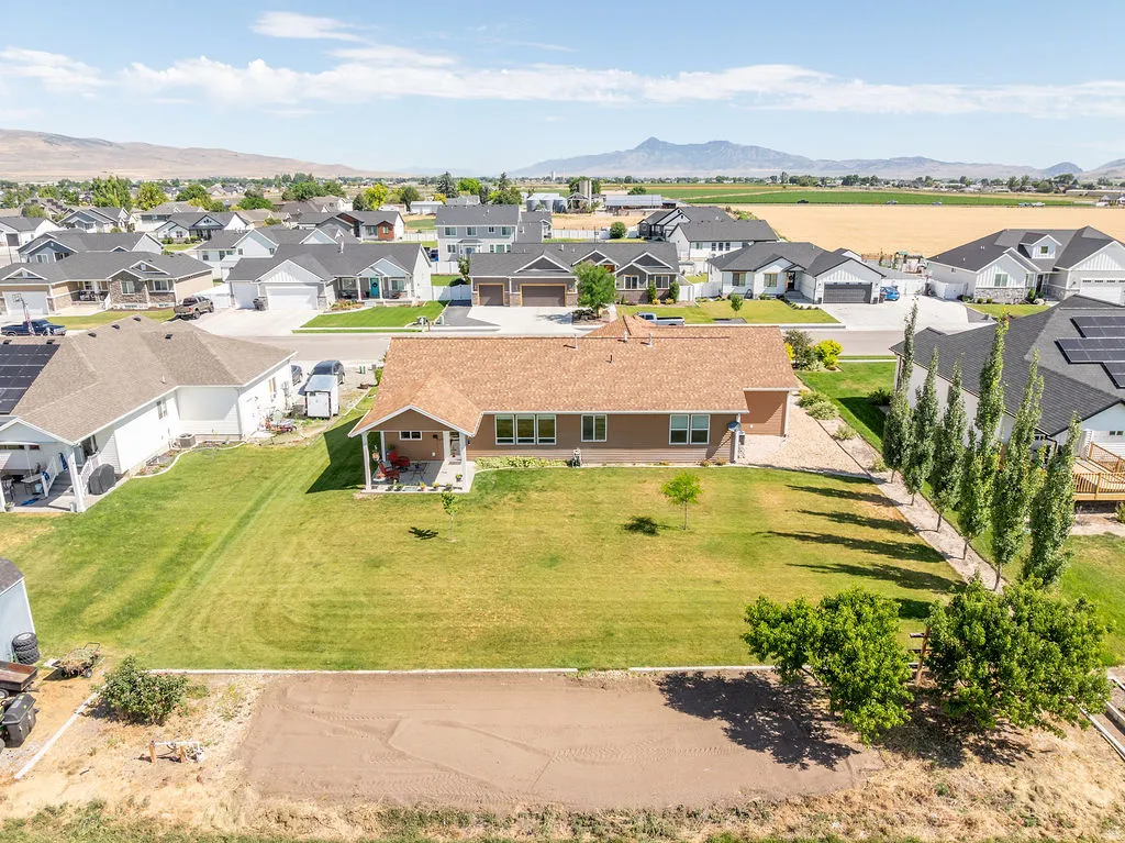 Expansive lawn with a covered back patio, mature trees, and landscaping elements, offering outdoor living space