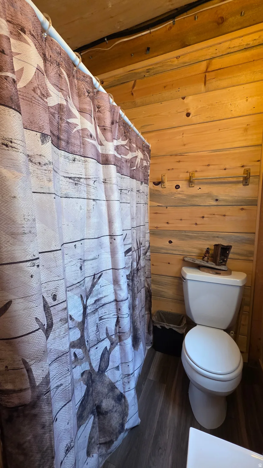 Bathroom featuring wood plank walls and wood-finish flooring