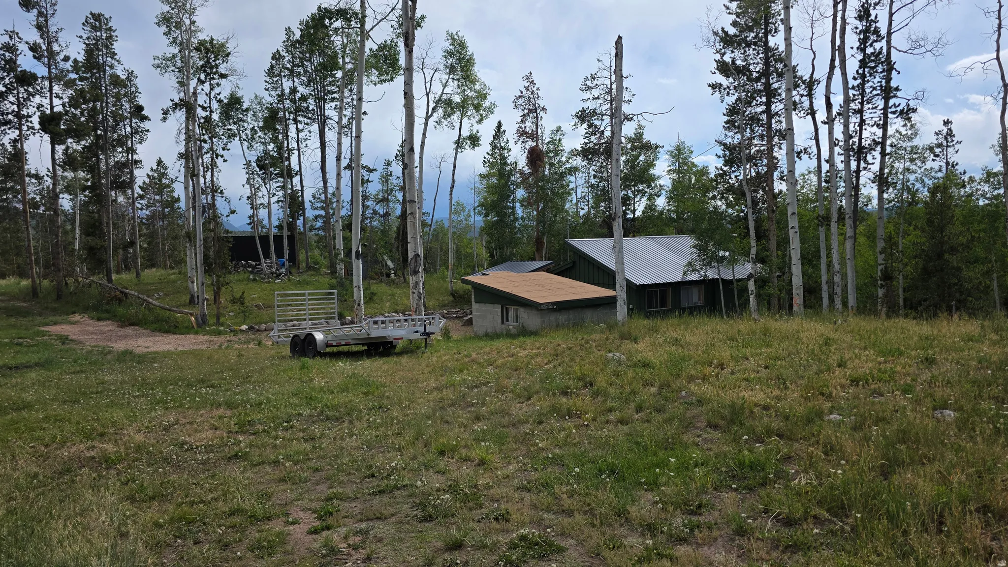 Property set amongst mature trees with a metal roof dwelling and a secondary structure featuring a flat roof