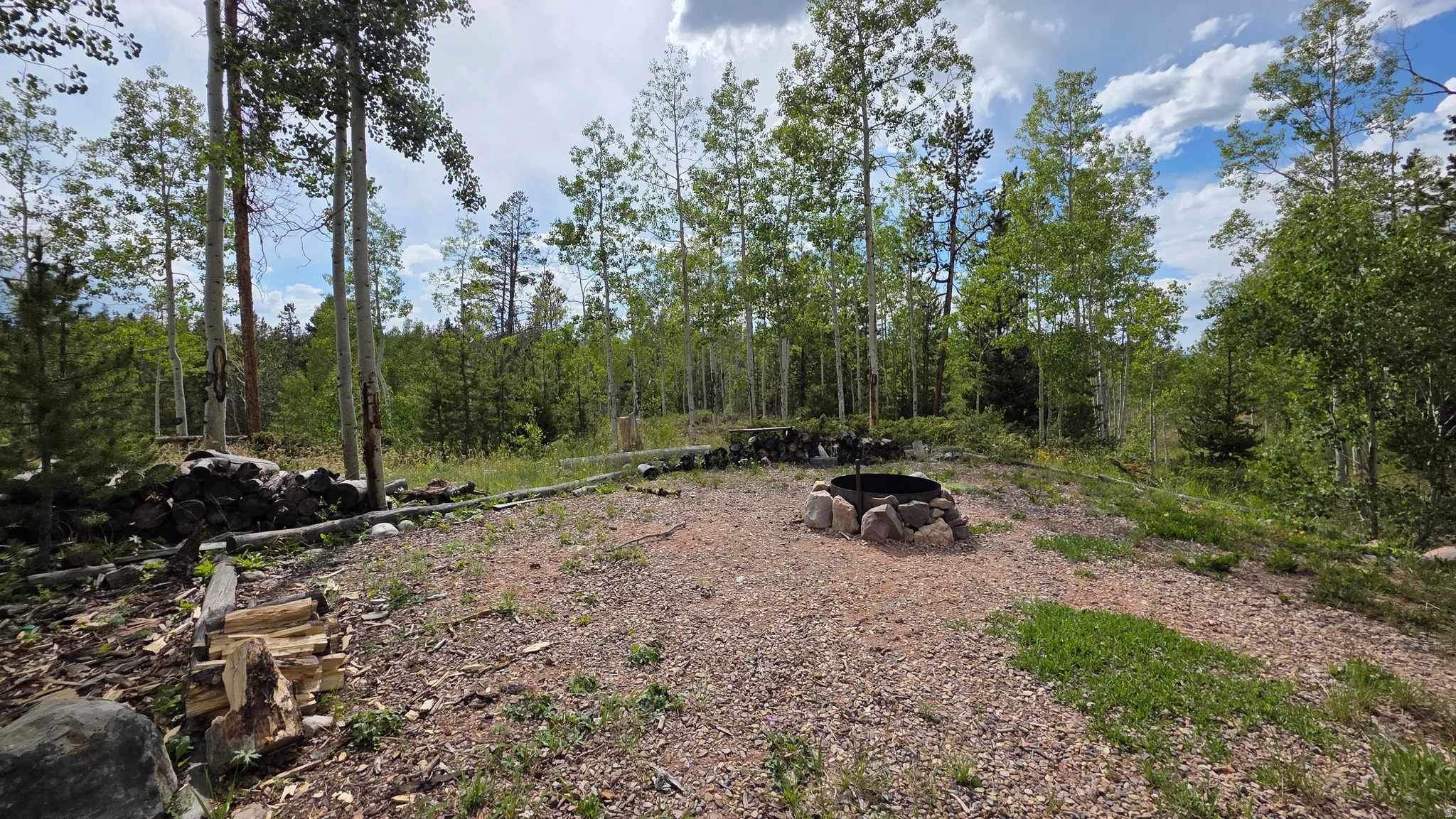 Expansive natural landscape featuring a central fire pit with a stone surround