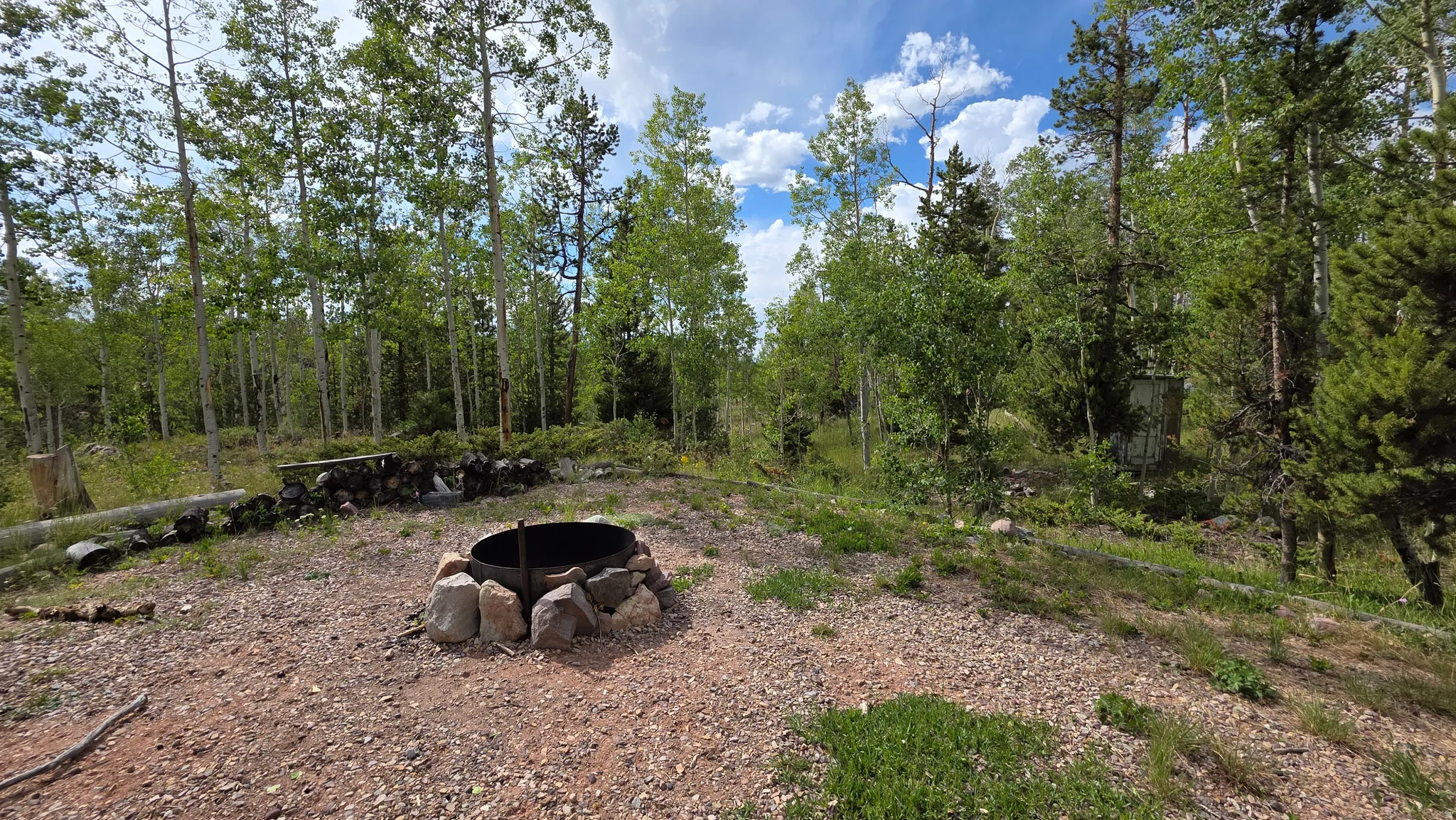 Expansive outdoor area featuring a circular metal fire pit surrounded by natural stones