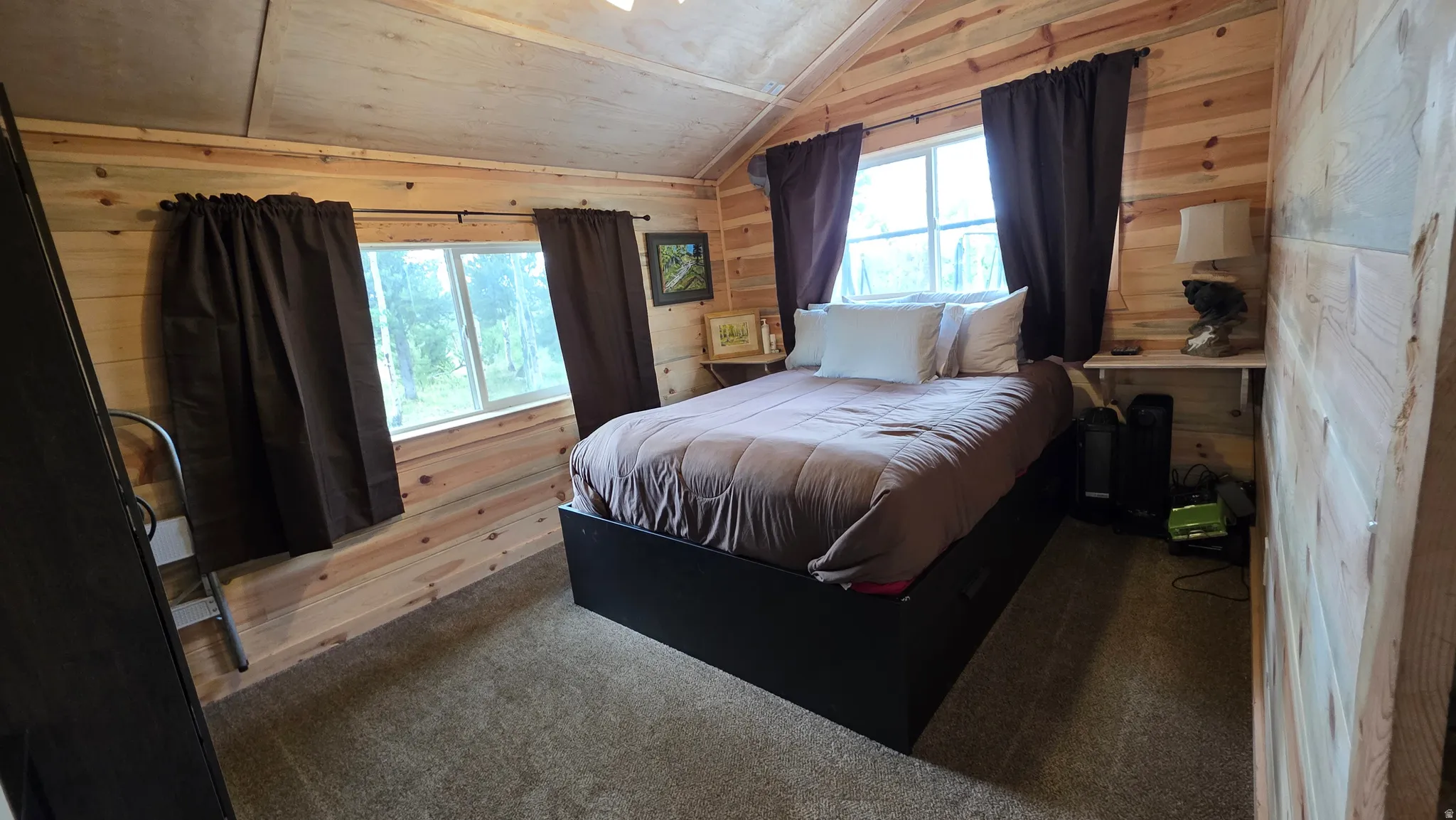 Interior room featuring wood-paneled walls, a carpeted floor, and a sloped wood-paneled ceiling