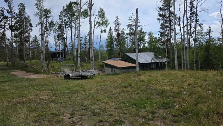Property set amongst mature trees with a metal roof dwelling and a secondary structure featuring a flat roof