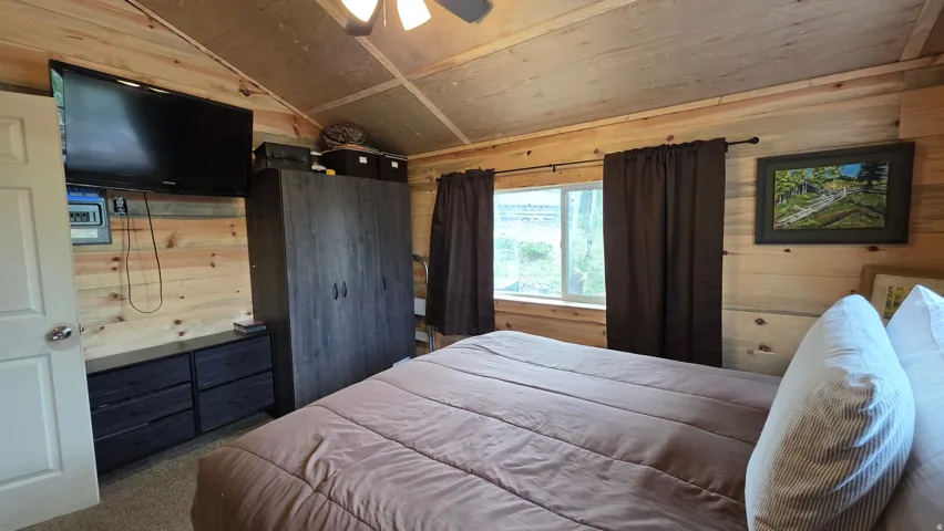 Wood-paneled interior room featuring a light wood ceiling with exposed beams
