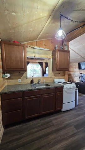 Kitchenette featuring dark wood cabinetry, a stainless steel sink, and speckled countertops