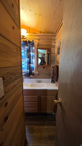 Compact bathroom featuring wood-finish wall paneling and sloped wood-finish ceiling