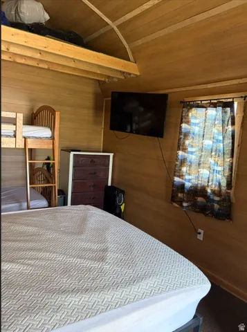 Wood-paneled interior featuring a built-in lofted area, bunk bed, and wall-mounted television