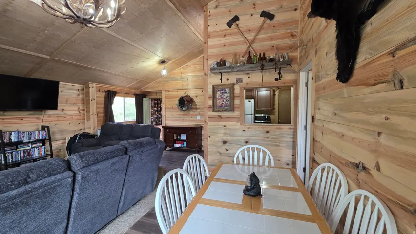 Interior space featuring natural wood paneling throughout, a vaulted ceiling, and a dining area with a tile-top table