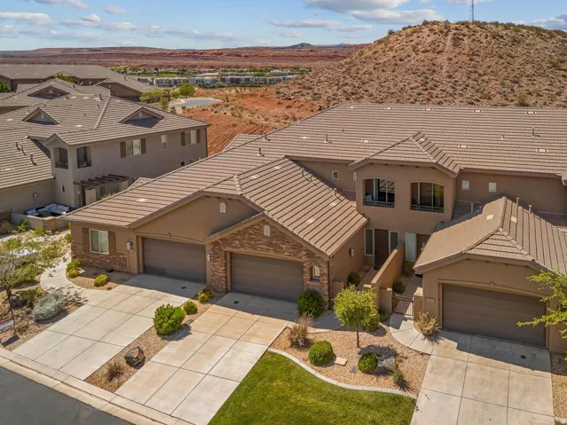 Multi-family residential property featuring a stucco exterior, tile roofing, and integrated garages with paneled doors
