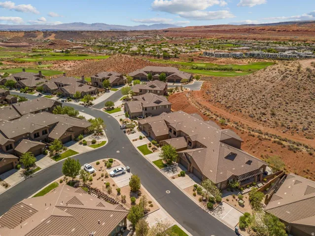 Aerial perspective of a residential community featuring multiple homes with tile roofs, mature landscaping, and an organized street layout
