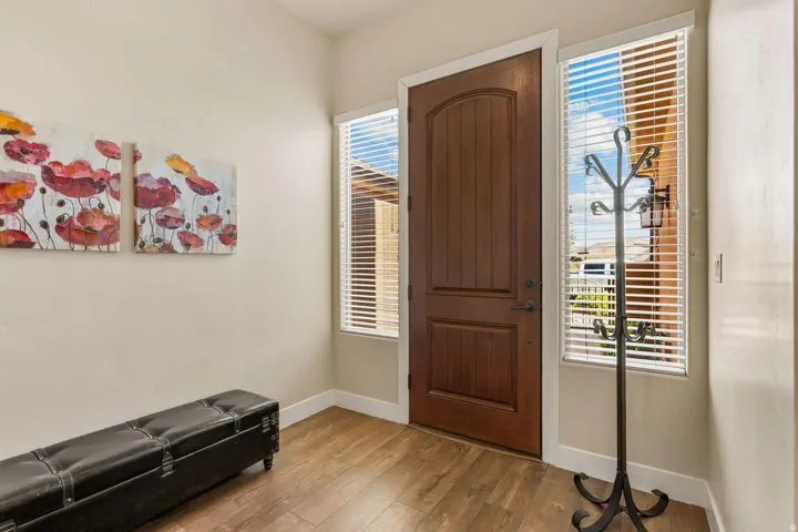 Entryway featuring a rich wood-paneled door with dark hardware, framed by two vertical windows with blinds