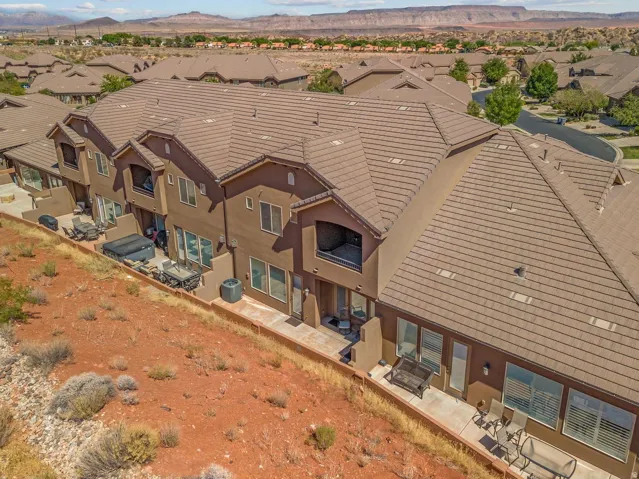 Multi-level townhome exterior featuring an upper balcony, ground-level patio space, and tile roofing