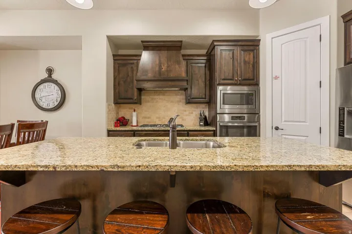 Kitchen island featuring a double basin sink and a light-toned granite countertop