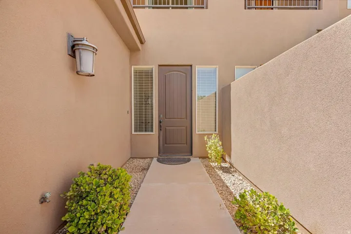 Entryway featuring stucco walls, a dark brown door, and sidelight windows with blinds