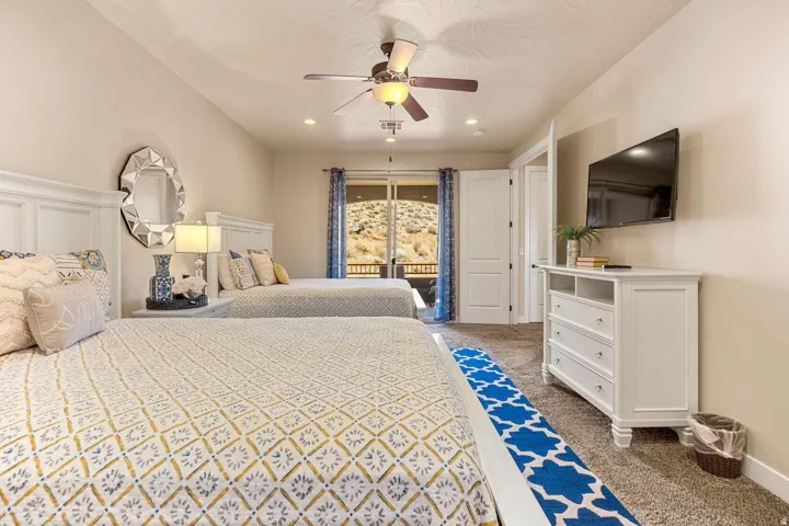 Carpeted room featuring two white panel headboards, a white dresser with built-in shelving, and a wall-mounted flat-screen television
