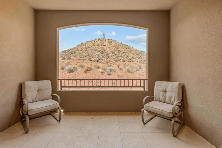 Arched window opening to a desert landscape, framed by textured walls and light-toned tile flooring