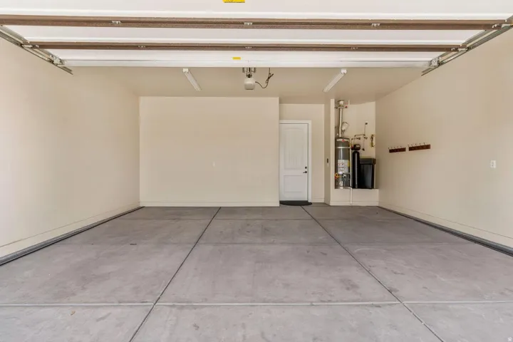 Spacious garage with concrete flooring, utility door, built-in shelving, and overhead fluorescent lighting