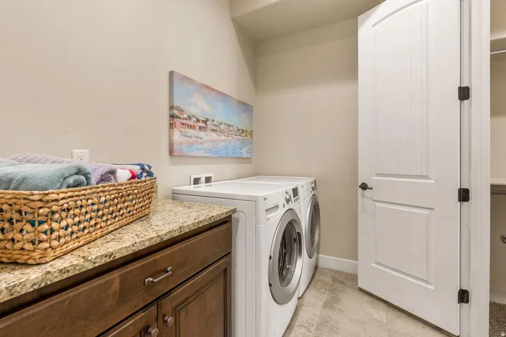 Laundry area featuring a granite countertop, wood-finish cabinetry with silver hardware, and light-toned wall paint