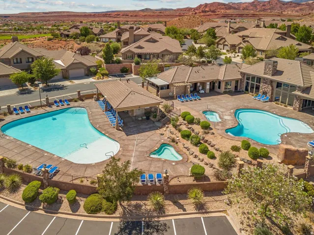 Community amenities featuring multiple swimming pools, integrated spas, a covered lounge area, and substantial stone architecture