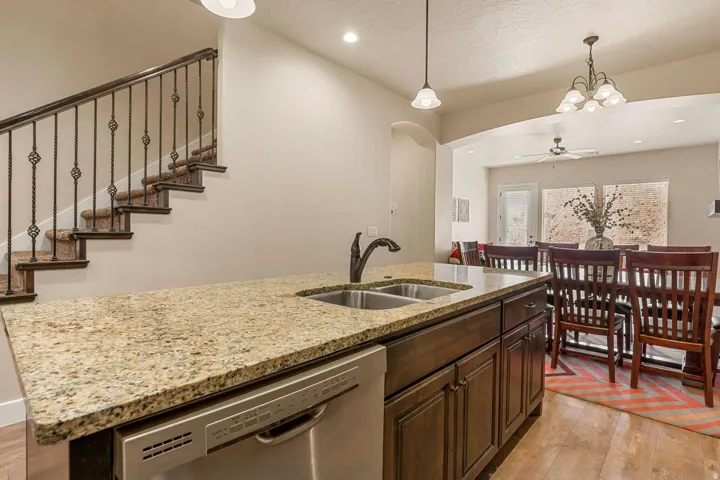 Kitchen island with a double basin sink, granite countertop, and integrated dishwasher