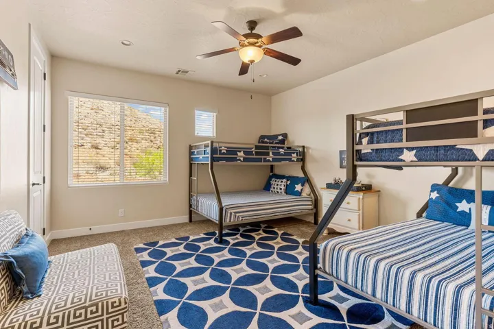 Carpeted room featuring a ceiling fan with light, white window blinds, and a door with black hardware