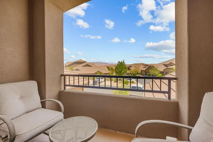 Balcony space featuring a stucco finish, a black metal railing, and a desert landscape backdrop