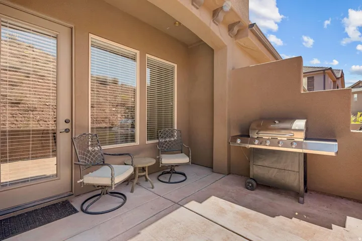 Covered patio featuring textured stucco walls, a full-lite glass door, and two horizontal windows with blinds