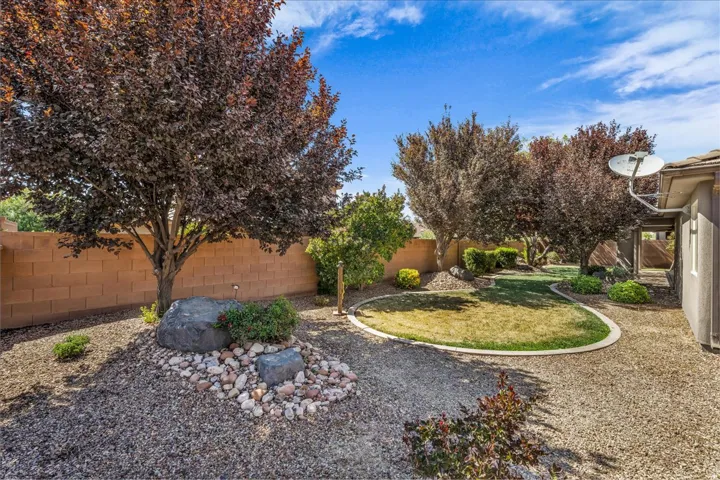 Landscaped backyard featuring gravel areas, mature trees, and a central lawn