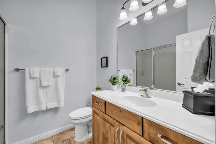 Bathroom featuring a single vanity with wood-finish cabinetry, a white countertop, and an integrated sink