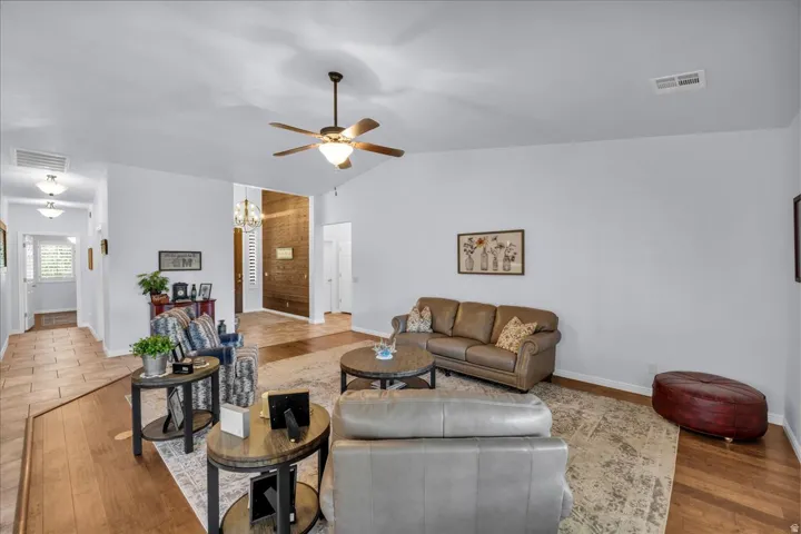 Spacious living area featuring vaulted ceilings, a ceiling fan, and wood-finish flooring