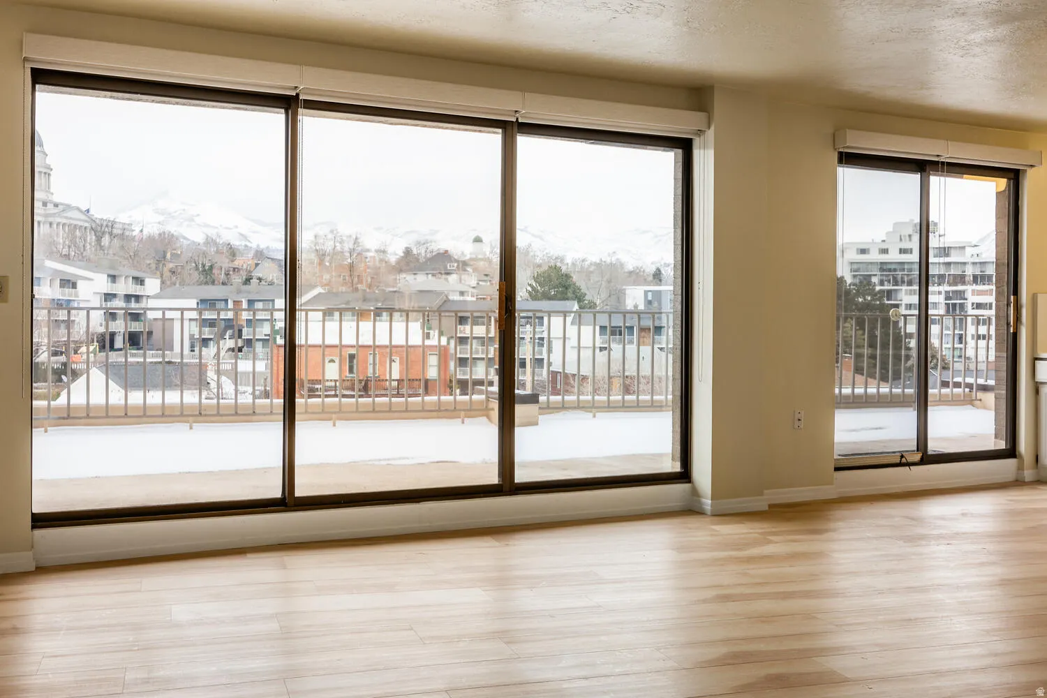 Expansive floor-to-ceiling windows featuring a metal balcony railing and wood-finish flooring