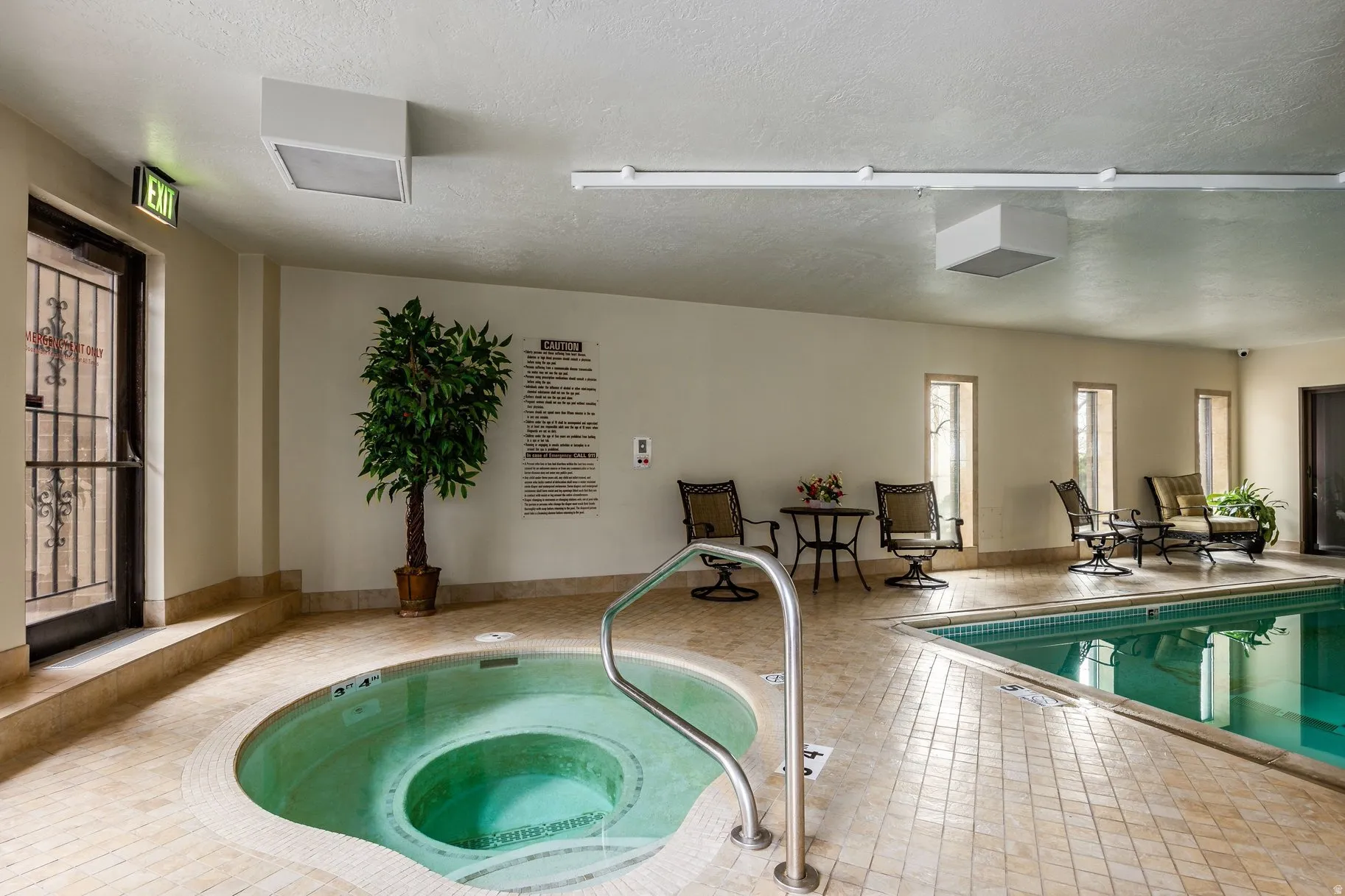 Indoor aquatic area featuring a large swimming pool and a circular spa