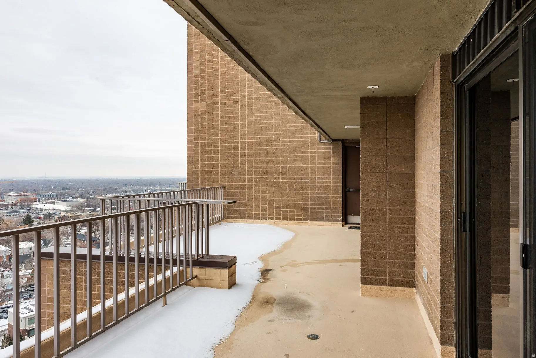 Expansive concrete balcony featuring metal railings and a cityscape backdrop