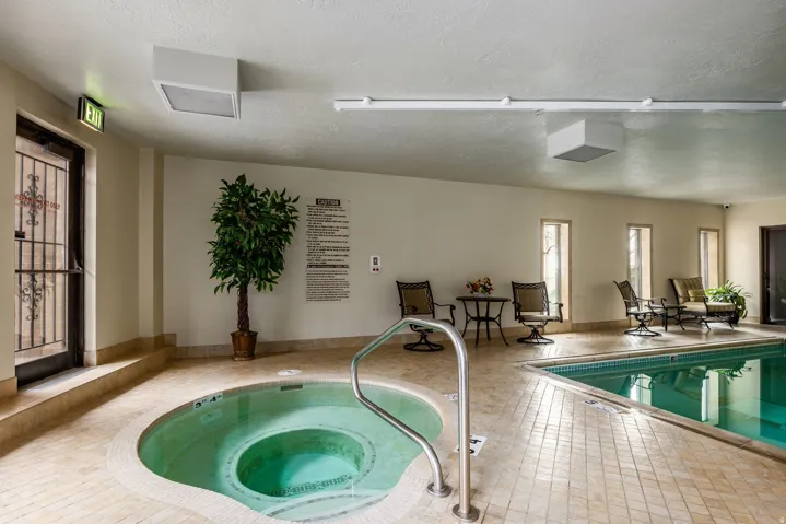 Indoor aquatic area featuring a large swimming pool and a circular spa
