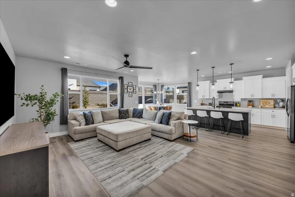 Spacious open-concept living area featuring wood-finish flooring, recessed lighting, and a modern ceiling fan